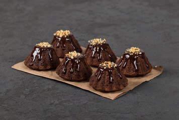 Vegan dessert chocolate cupcakes with icing and nut sprinkles on paper on a dark gray background