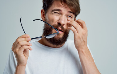 man touches eyes with hands and glasses vision problems gray background