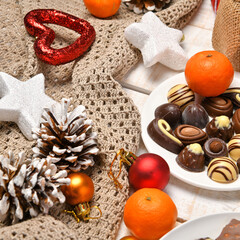 Fototapeta na wymiar sweet food top view background for merry christmas or new year holiday decoration - chocolate candies, tangerines, cookies on white wood