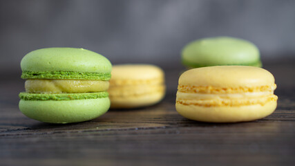 Close up vibrant green and yellow macaroons on wooden table