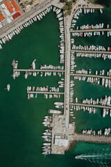 Aerial drone view of Marina on greek Aegina Island with many parking boats and yachts during sunlight.