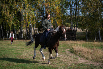 Cute girl equestrian instructor rides a horse in an equestrian club.