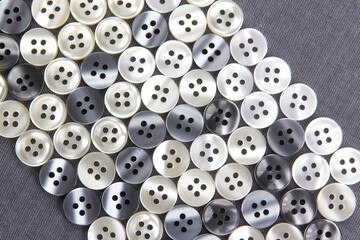 Obraz premium Plastic shiny buttons for clothes on a fabric background. Fashion and clothing. Factory industry