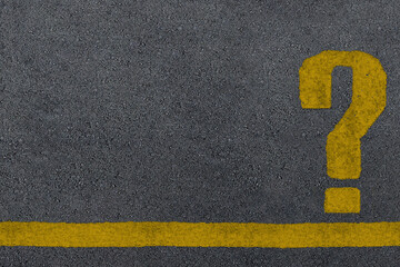 Yellow question mark sign painted on a asphalt road surface