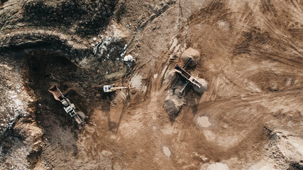 Aerial top down of Vast Excavation Site With Multiple Heavy Industry Vehicles during sunset after work.