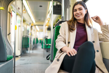 Fototapeta na wymiar Cheerful woman rides in the city tram. Young female passenger sits in public transport
