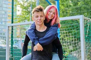 Couple of teenagers guy and girl having fun on an outdoor basketball court