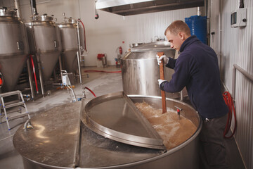 Professional brewer working at automated microbrewery, copy space