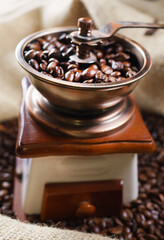 Vintage old coffee grinder with coffee beans in bag.