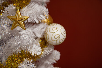 Christmas decoration on a white tree on the left of the image with a red background.