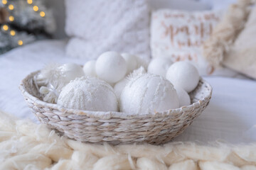 Christmas eco decorated bedroom interior, comfortable bed, knitted white bedspread. Copy space. Cozy home moment. Happy New Year. Holiday morning. Wicker basket decorative ornaments handmade balls