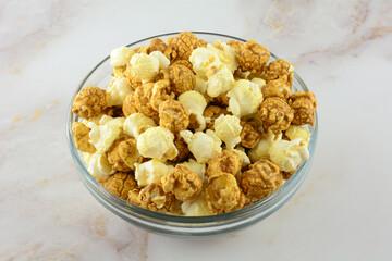 Caramel and cheddar popcorn on glass snack bowl on table