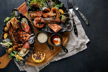grilled seafood platter. Assorted delicious grilled seafood with vegetables. Grilled mixed bastards with pepper sauce and vegetables. Black background