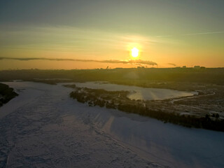 the sun rises over the city located on the banks of the river on a frosty winter morning