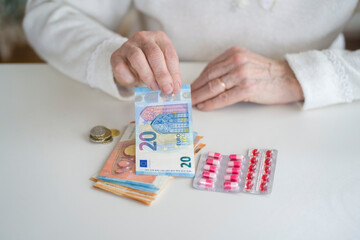 An older retired woman is counting money and saving it for medicines, medical treatment and insurance. Taking care of your health and wise investment.