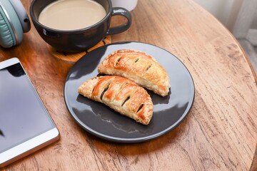 Red bean puff on the plate with a cup of coffee, and a smartphone on the wooden table 