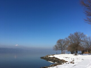 Winter scene, park, river, snow, blue sky, bare trees