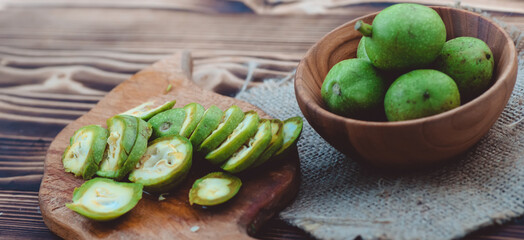 healthy food. Walnuts, cut into slices, are scattered on a cutting board. Old vintage table and whole unripe walnut fruit