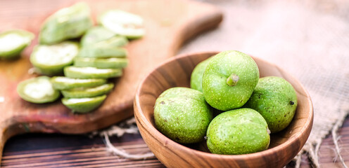 healthy food. Walnuts, cut into slices, are scattered on a cutting board. Old vintage table and whole unripe walnut fruit