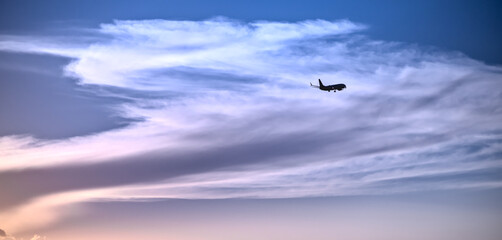plane silohuette flying over beautiful massive cloud on a sunset sky, painterly abstract 