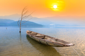 Obraz premium Fishing boat in the big lagoon at sunset sky. This is the main means of transportation to catch fish of fishermen in central Vietnam