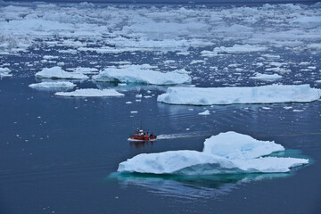 A red fishing boat passes icebergs in Disko Bay as it returns to port at Ilulissat, Greenland.