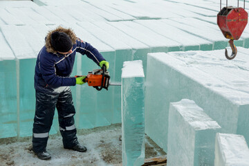 Work installer with a chainsaw in his hands undercut ice block