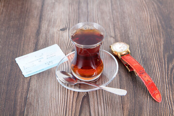 A cup of black tea and a train ticket and a watch