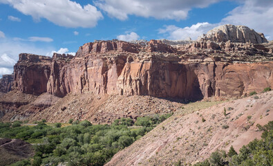 Fototapeta premium Golden sandstone geographical formations with a desert prairie landscape on a hot summer day at the Cohan Canyon Trail in Capitol Reef National Park Southern Utah.