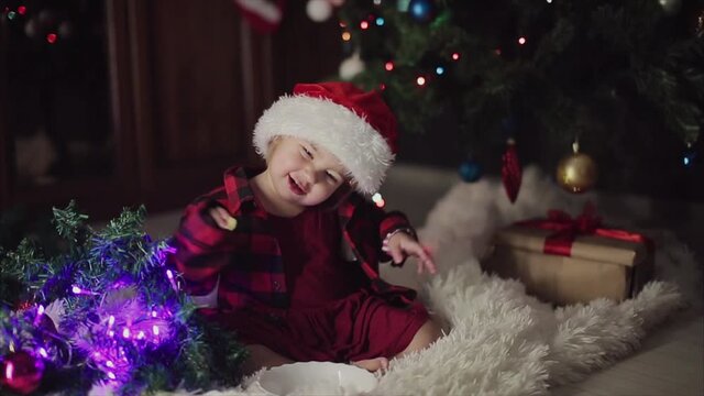 a child in red clothes is sitting waiting for the new year. the concept of celebrating Christmas at midnight. holiday costume. a girl writes a letter to Santa Claus. wish list