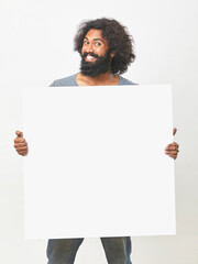 Cheerful bearded young man holding white board on white background.