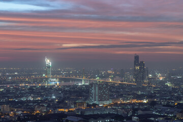 Bangkok, thailand - Dec 23, 2020 : Aerial view of Bangkok city Overlooking Skyscrapers and the Bridge crosses the Chao Phraya river with bright glowing lights at dusk. No focus, specifically.