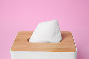 Holder with paper tissues on pink background, closeup