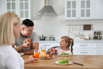 Happy family having breakfast together at table in modern kitchen