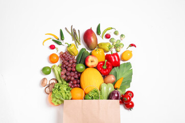 Paper bag with assortment of fresh organic fruits and vegetables on white background, top view