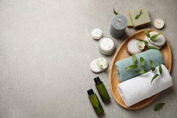 Flat lay spa composition with skin care products on grey textured table, space for text