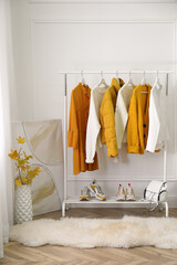 Rack with stylish warm clothes, shoes and accessories in modern dressing room