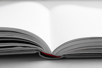 Open book with hard cover on light grey table, closeup