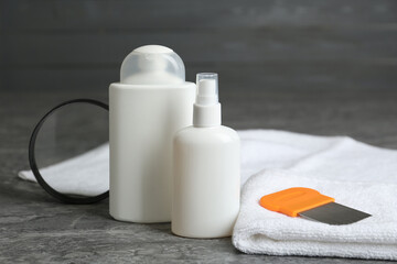 Cosmetic products, lice comb, magnifying glass and towel on grey table