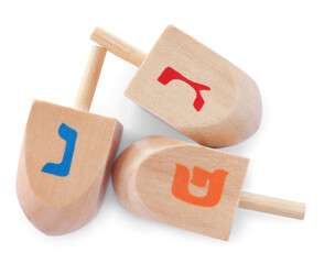 Wooden Hanukkah traditional dreidels with letters Nun, Gimel and Pe on white background, top view