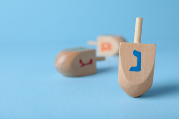 Hanukkah traditional dreidel with letter Nun on light blue background, space for text