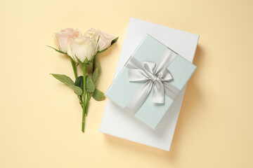 Elegant gift boxes and beautiful flowers on beige background, flat lay