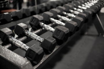 A rack of rubberized hex dumbbells at a gym or fitness club. Workout and pyramid training or...