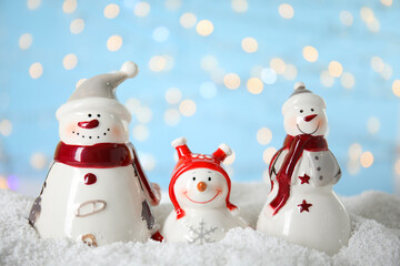 Decorative snowmen on artificial snow against blurred festive lights