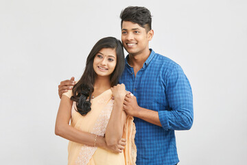 Cheerful Indian young couple in traditional outfit against white.
