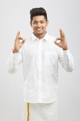 Cheerful handsome south Indian man showing ok sign on white.