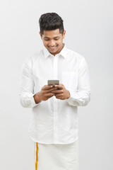 Traditional south Indian young man using smartphone on white
