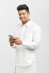 Traditional south Indian young man using smartphone on white