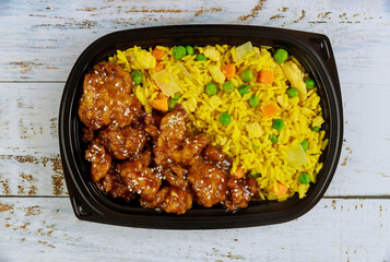 Teriyaki chicken with rice and vegetables in plastic food container.