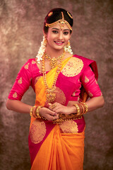 Fototapeta premium Beautiful smiling Indian bride with jewelry in studio shot.